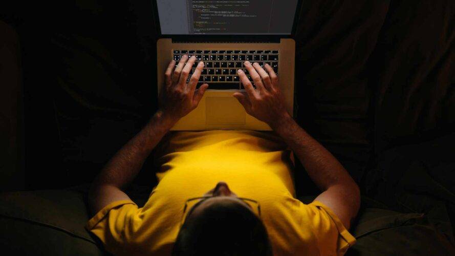 Person arbeitet am Laptop im Dunkeln