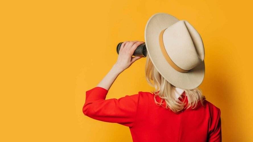 Frau mit Fernglas vor gelbem Hintergrund