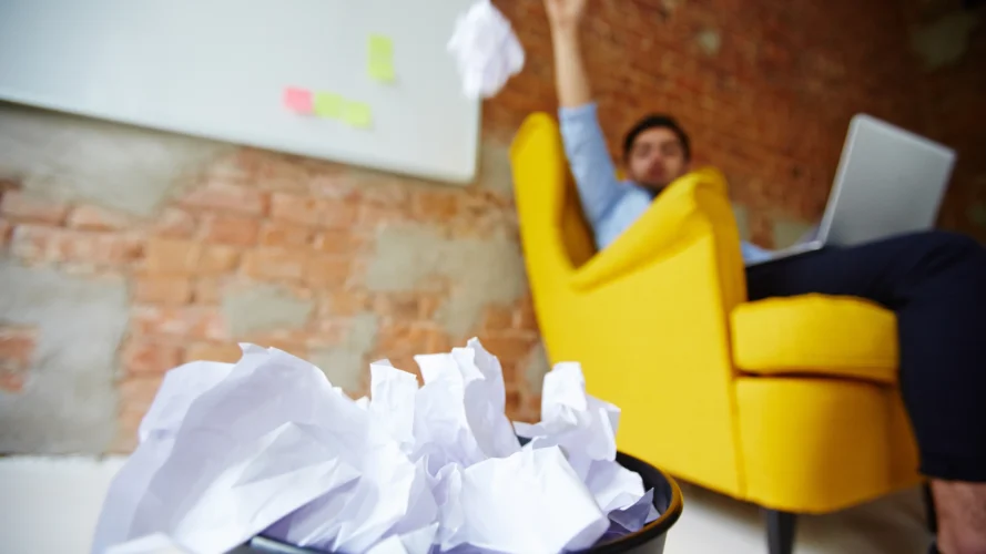 Mann wirft Papier in Mülleimer im Büro